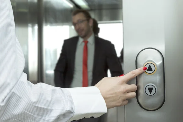 Female hand pressing elevator up button. Businessman inside of the elevator.