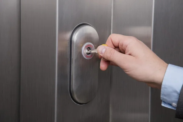 Close up of a hand putting the key in fireman service lock on the elevator