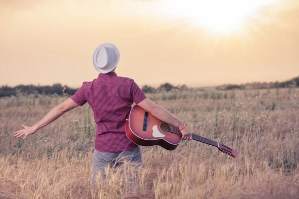 Young man with acoustic guitar enjoying the sunset