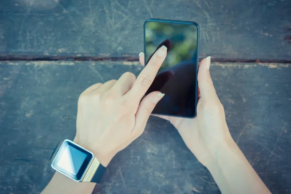 Close up of female hand holding smart phone and wearing watch