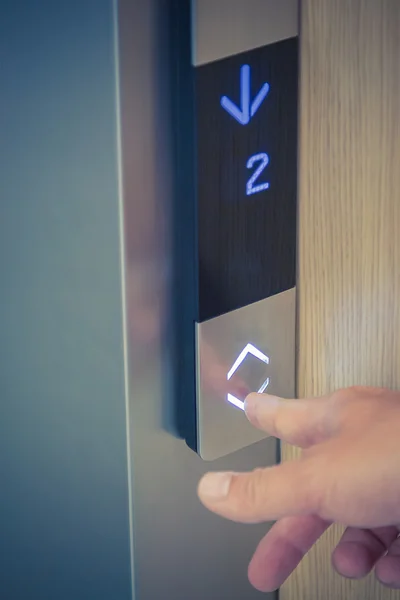 Male finger pushing elevator down button