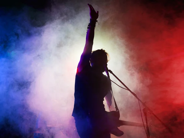 Silhouette of guitar player on stage.