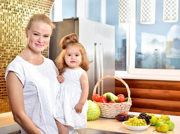 Happy young mother with a baby in the kitchen
