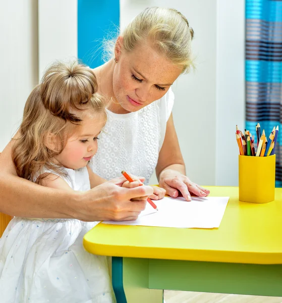 Mother teaching daughter draw with pencils
