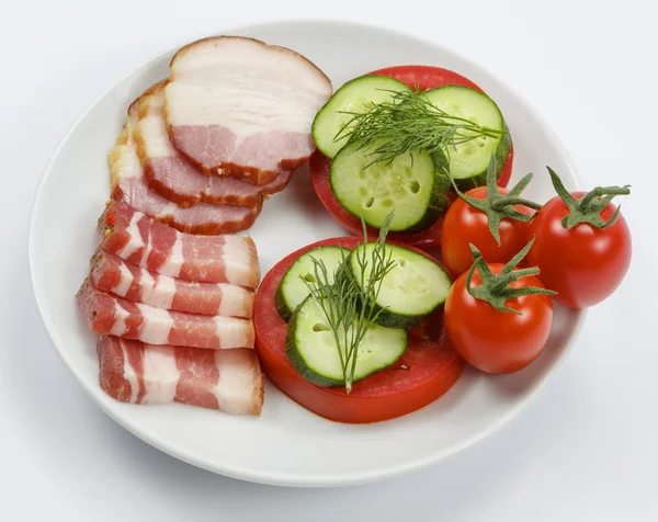 Slices of bacon with tomatoes and cucumbers on white background