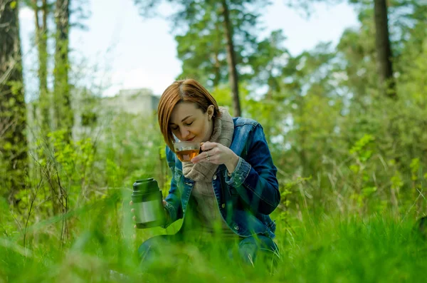 Lonely girl enjoying a cup of green tea in the forest