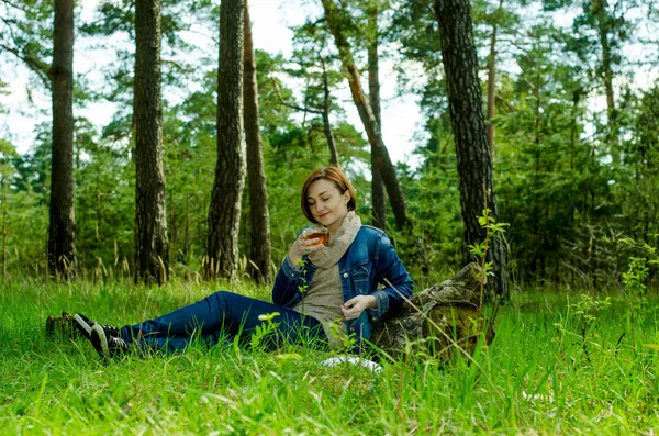 Lonely girl enjoying a cup of green tea in the forest