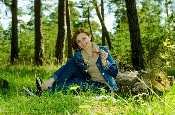 Lonely girl enjoying a cup of green tea in the forest
