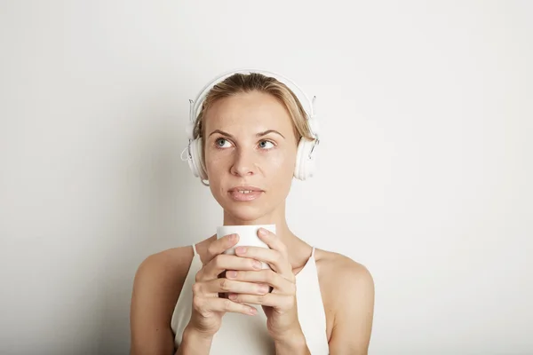 Portrait Handsome Young Woman Listening Music Player Headphones Blank White Background.Pretty Girl Dreaming Holding Coffe Cup Hands Empty Wall.Beauty Lifestyle Fashion Hipster People Abstract Concept.