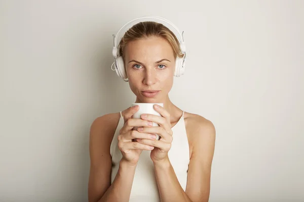 Portrait Handsome Young Woman Listening Music Player Headphones Blank White Background.Pretty Girl looking Holding Coffe Cup Hands Empty Wall.Beauty Lifestyle Fashion Hipster People Concept.Closeup.