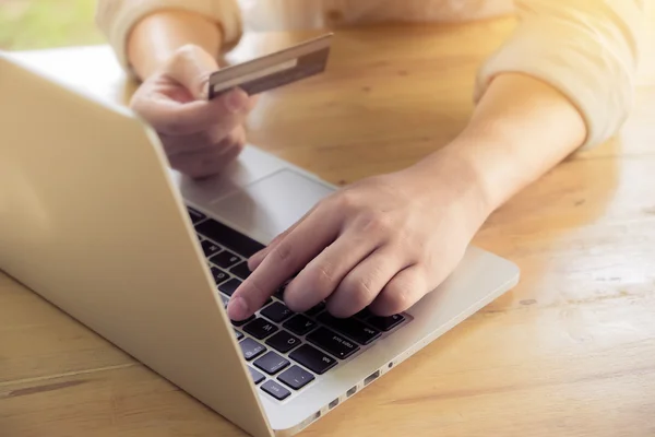 Man\'s hands holding a credit card and using pc or laptop for online shopping.