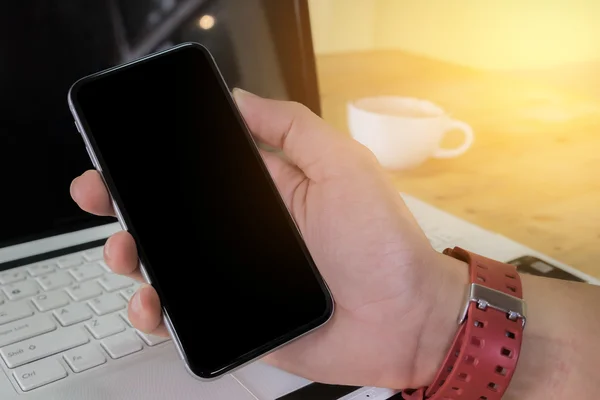 Close up of a man using smart phone with blank mobile and cup of coffee .Smart phone with blank screen and can be add your texts or others on smart phone.