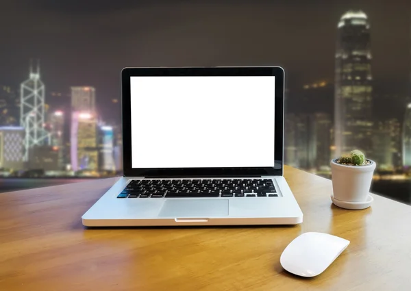 Front view of laptop on table in Office and night building blurred background