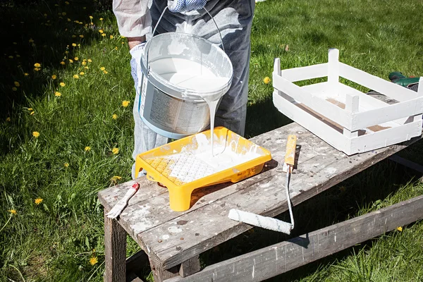 Man pour paint in paint dish. Outdoor work. Sunny day.