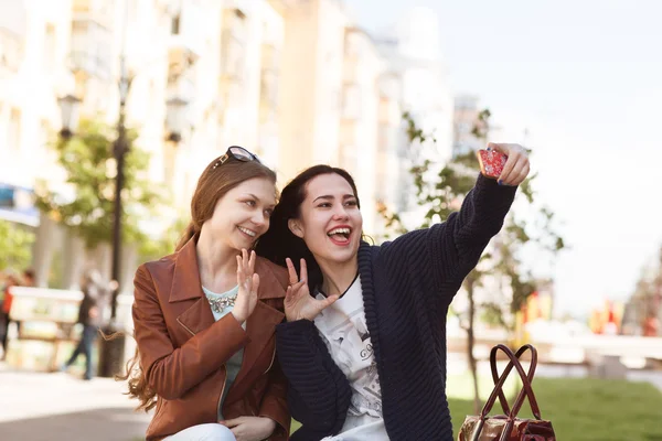 Two young women friends having fun in city taking selfie