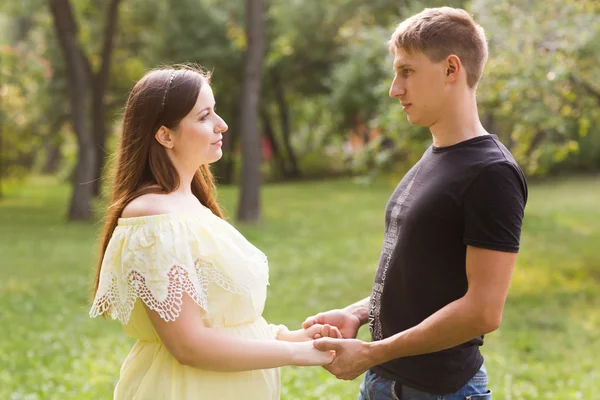 The young beautiful pregnant woman with the husband in park in summer day