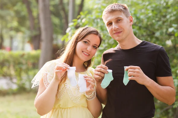 Happy couple announcing pregnancy. Parents hold socks for the newborn.