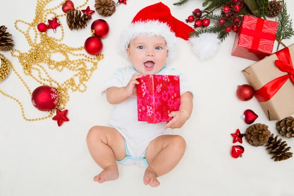 Baby first christmas. Beautiful little baby celebrates Christmas. New Year's holidays. Baby with santa hat with gift