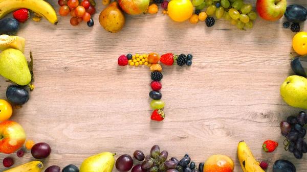 Fruits made letter T. Alphabet on a table. Fruits are forming letters
