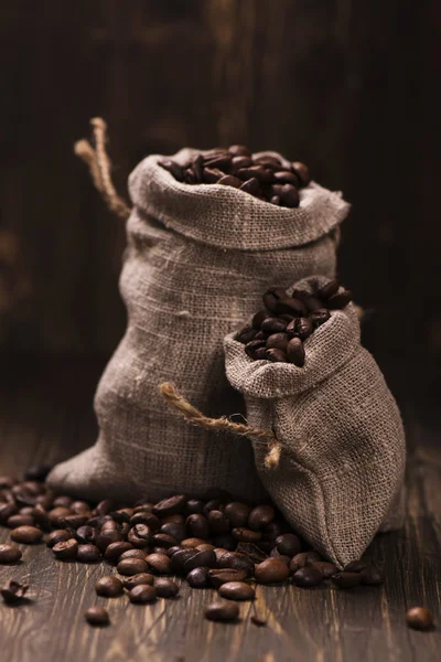 Coffee beans in burlap bags over wooden background