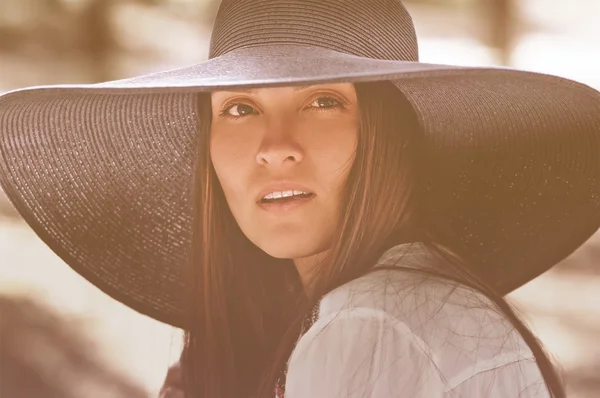 Portrait of an adult girl in a black hat