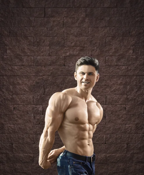 Young fit man is smiling and showing muscles -- toned and styliz