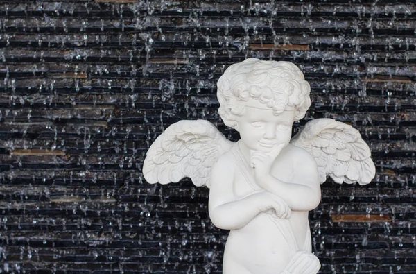 White plaster statue angle cupid on a brick wall background