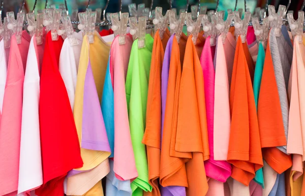 Colorful choice of casual clothes on wooden hangers in the market