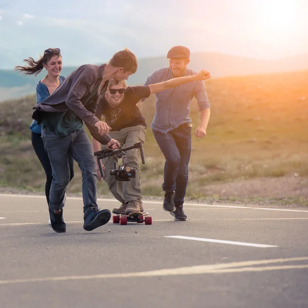 Group of friends run, laugh and shoot with the camera on the electronic suspension, the guy the longboard