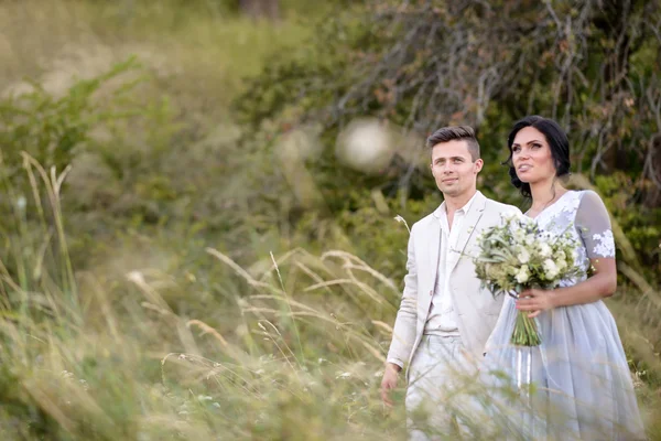 Young couple in love outdoor. Elegant bride and groom posing together outdoors on a wedding day. bride and groom in the Park. young couple in the woods. young couple in the grass. couple walking