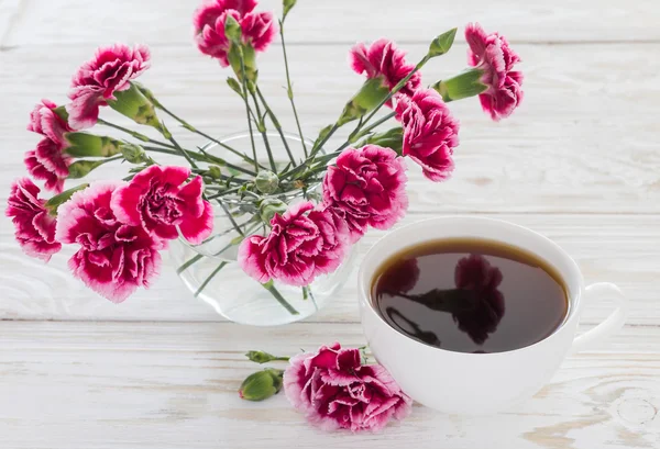 Cup of coffee and pink carnations