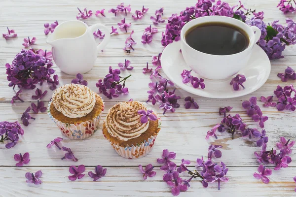 Cupcakes with cream, coffee, notebook and flowers