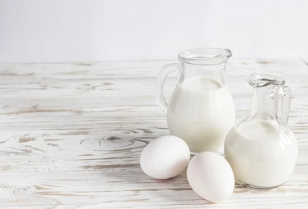 Milk jars and eggs on wooden background