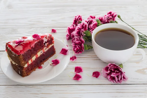 Red velvet cake, cup of coffee and pink carnations