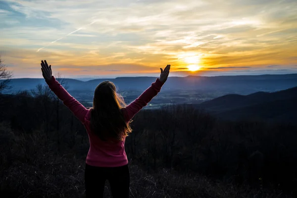 Happy girl raised her hands up to the sun, against the mountain