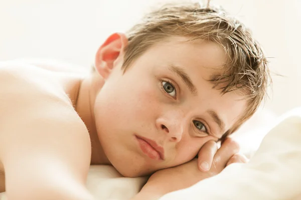 Teenage Boy Lying on Bed with Head on Hands