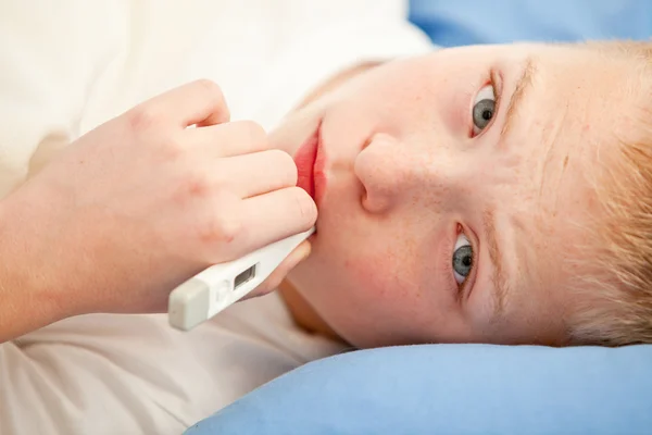 Close up view on sick boy using thermometer