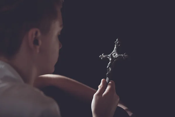 Contemplative Teenage Boy Holding Ornate Cross