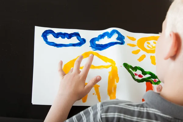 Young boy creating a colorful finger painting