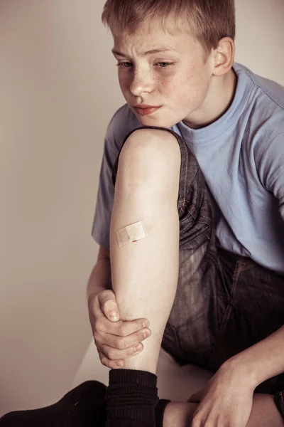 Young boy holding leg with bandage on shin