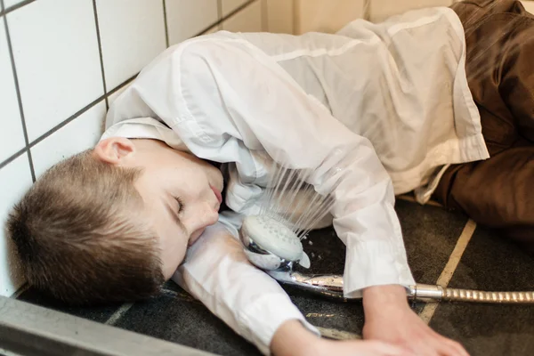 Fully clothed boy unconscious on shower floor