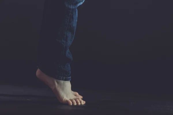 Close up of bare feet standing on dark floor