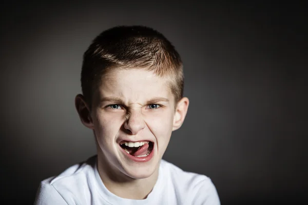 Solitary boy making faces against black background