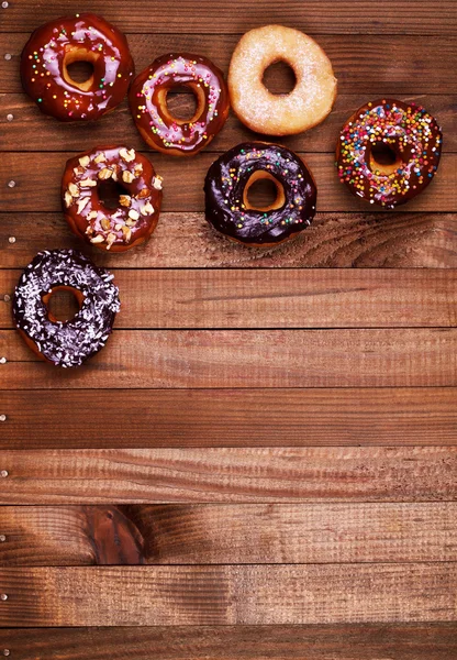 Bright donuts on wooden background.