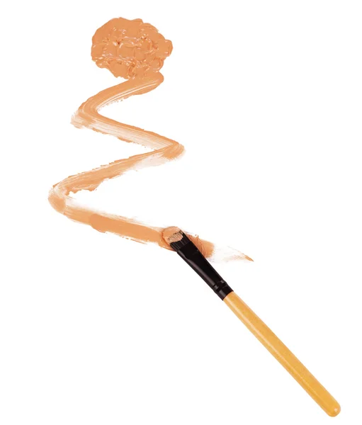 Close-up of makeup brush with smeared liquid foundation on white