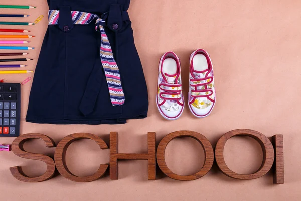 School uniform near sneakers and  supplies on orange background with an inscription . Top view, Copy space. outfit. Back to .