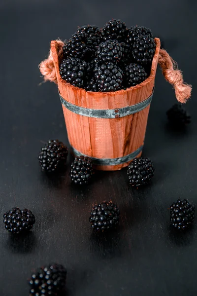 Black raspberries in a wooden basket and on  table. Copy space.
