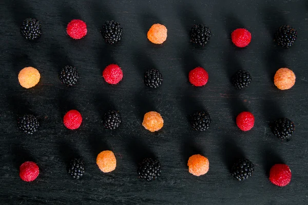 Mixed of red, black, yellow raspberries on  table. Close up.