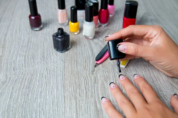 Black nail polish being applied to hand with tools for manicure on background. Beautiful  process.  Top view. Copy space. Frame.