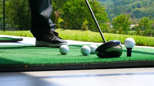 Close up ball on tee retired golfer taking swing hitting golf ball off tee on golf course